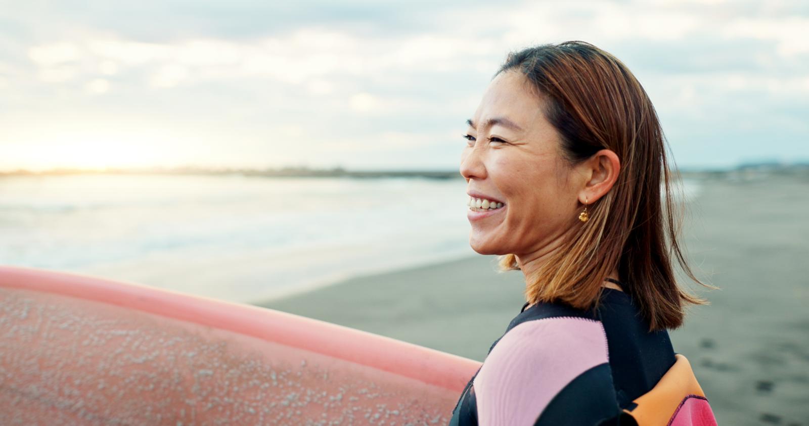 Middle aged straight hair feminine person on beach smiling